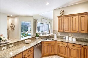 A modern kitchen with granite countertops, wooden cabinets, and a large window offering a view of the outdoors. - Brilliant 4-bedroom house Casa Paraiso 'House of Paradise' in charming Naples (Naples)