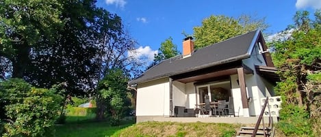 A house with a covered patio, a chimney, and a staircase leading up to the entrance.