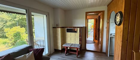 Una habitación con un banco de madera, un sofá, una puerta de madera y vistas al exterior con vegetación.