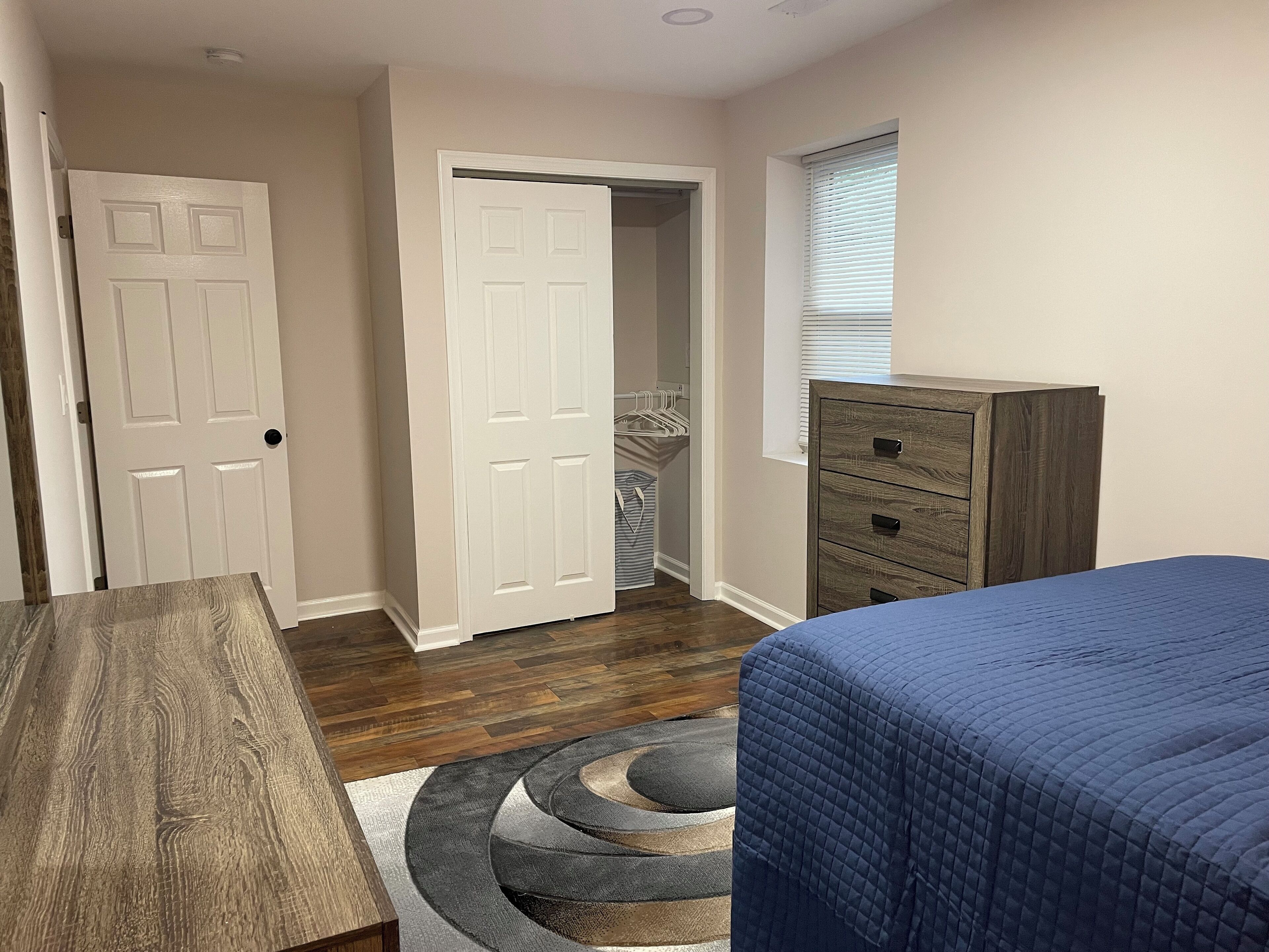A bedroom with a bed, a dresser, a door, and a closet.