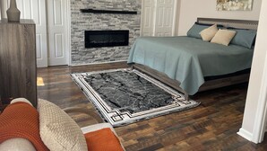 Une chambre avec un mur en pierre, une cheminée, un lit avec des oreillers et un tapis.