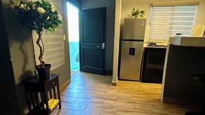 Eine kleine Küche mit Kühlschrank, Herd und einem Blumentopf.