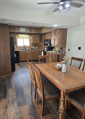 Una cucina con mobili in legno, un tavolo da pranzo con sedie e una ventola a soffitto.