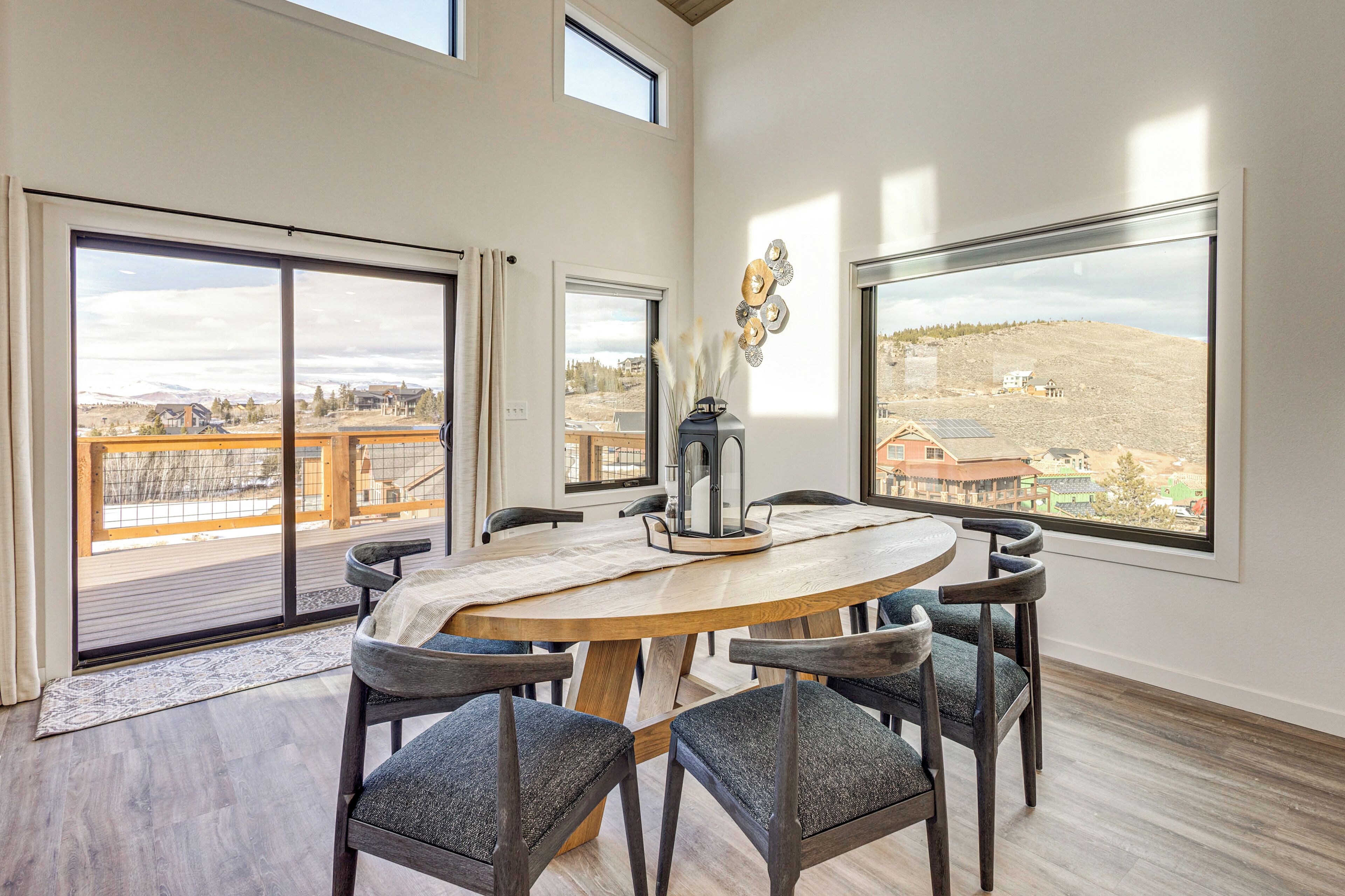 A dining area with a round table, six chairs, and large windows offering views of a cityscape.