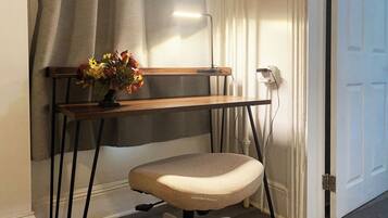 A desk with a chair, a power outlet, and a door in the background.