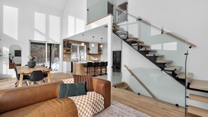 Een modern interieur met een houten eettafel, een leren bank en een glazen trap.