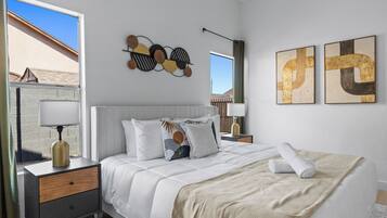 A neatly arranged bedroom with a bed, bedside tables, and artwork on the walls.