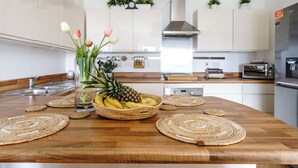 A kitchen with a wooden countertop, a bowl of fruit, and a vase with flowers. - Newport City Centre Riverside haven (Newport)