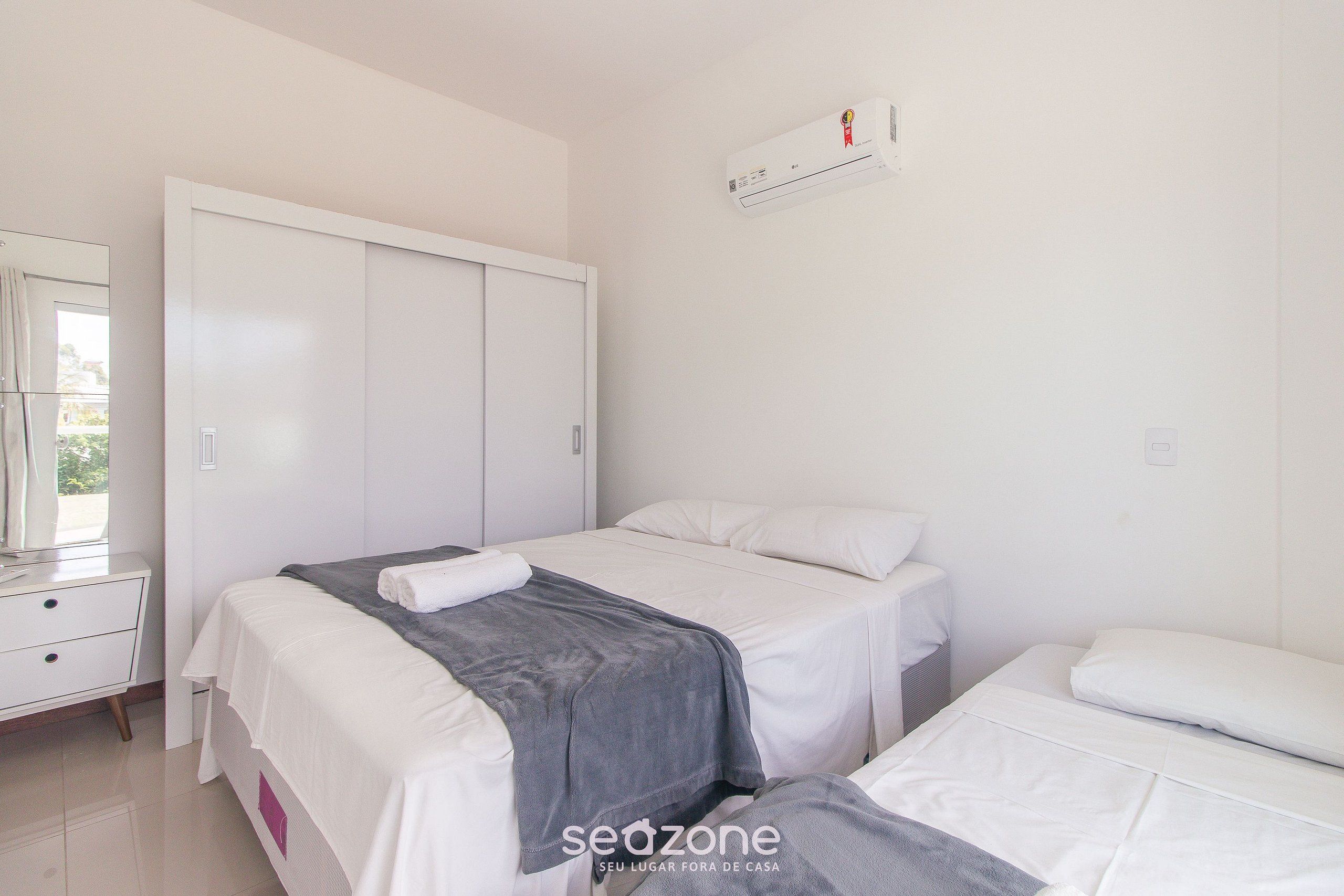 A bedroom with two beds, a wardrobe, a mirror, and an air conditioner.