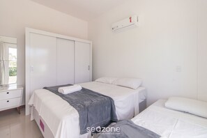A bedroom with two beds, a wardrobe, a mirror, and an air conditioner. - 2-bedroom Apt 550m From the Beach Chv0102 (Florianópolis)