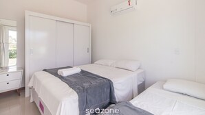 A bedroom with two beds, a wardrobe, a mirror, and an air conditioner. - 2-bedroom Apt 550m From the Beach Chv0102 (Florianópolis)
