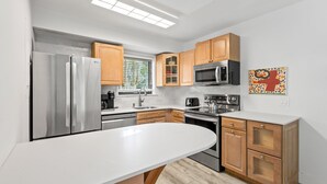 Eine moderne Küche mit Edelstahlgeräten, Holzschränken und einer weißen Arbeitsplatte.