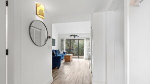 Ein modernes Wohnzimmer mit einem blauen Sofa, einem Holztisch und einem großen Fenster mit Vorhängen.