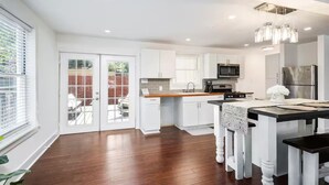 Una cocina moderna con armarios blancos, encimera de madera y electrodomésticos de acero inoxidable.