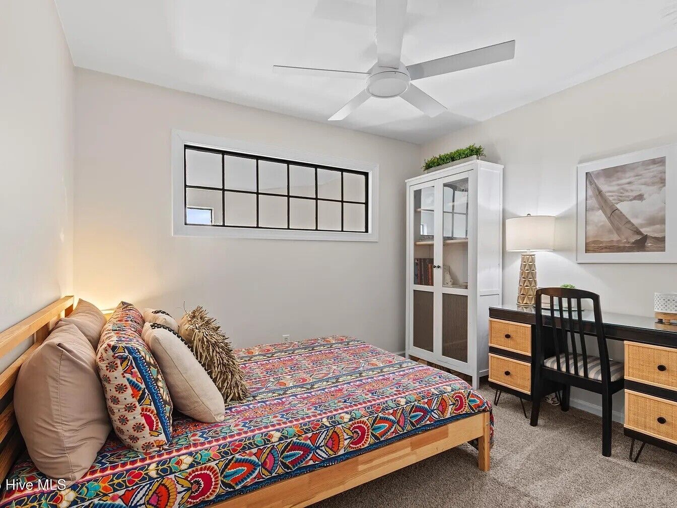 A bedroom with a bed, a desk, a chair, a wardrobe, and a ceiling fan.