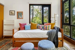 A bedroom with a wooden bed, colorful pillows, a large window, and a white dresser. - Glass Grove (Atlanta)