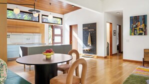 Eine moderne Küche mit Holzausstattung, ein Essbereich mit rundem Tisch und eine Treppe zu einer weiteren Ebene.