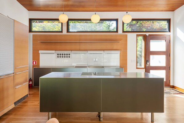 A modern kitchen with wooden cabinets, a stainless steel island, and pendant lights. - Glass Grove (Atlanta)