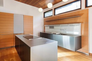 A modern kitchen with wooden cabinetry, a stainless steel island, and a built-in oven. - Glass Grove (Atlanta)