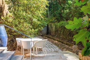 An outdoor patio with a table and chairs, surrounded by greenery and a stone wall. - Glass Grove (Atlanta)