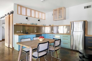 A modern kitchen with a wooden table, blue cabinets, and a stainless steel refrigerator. - Glass Grove (Atlanta)