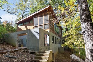 A modern two-story house with large windows and a wooden exterior, surrounded by trees and a concrete foundation. - Glass Grove (Atlanta)