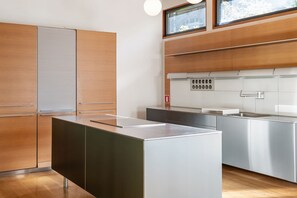 A modern kitchen with stainless steel appliances, wooden cabinets, and a large island. - Glass Grove (Atlanta)