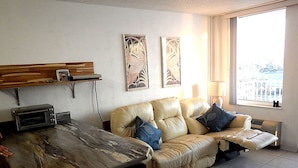 Een woonkamer met een bank, een eettafel en een raam met uitzicht.