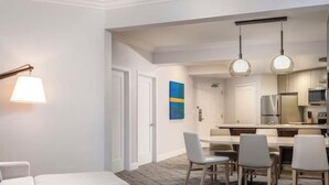 A modern hotel room with a sofa, a small table with a plant, a dining area with chairs, and a kitchen in the background. - HUGE DISCOUNT: 2-bedroom 2-bath Marriott Villa in gorgeous Newport Beach (Newport Beach)