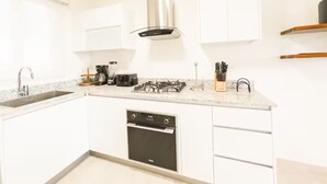 Ett modernt kök med vita skåp, en rostfri köksfläkt, en inbyggd ugn och en diskmaskin.