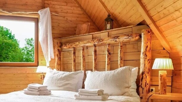 A wooden cabin bedroom with a bed, pillows, and a nightstand. - Etno house Molendini (Čatrnja)