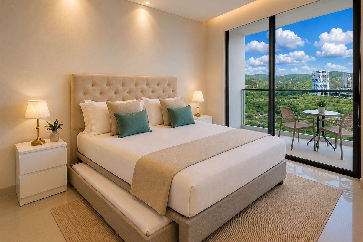 A modern bedroom with a large bed, bedside tables, a view of greenery and buildings through a large window.