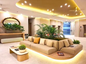 Eine moderne Lobby mit einer Couch, einem Couchtisch, einem Spiegel und Pflanzen.