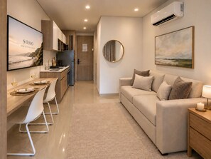 Un espace de vie moderne comprenant un canapé, une table à manger avec des chaises, une cuisine en arrière-plan et des œuvres d’art accrochées aux murs.