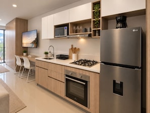 Une cuisine moderne équipée d’un réfrigérateur en acier inoxydable, d’un four à micro-ondes, d’une cuisinière à gaz et de meubles de rangement en bois.