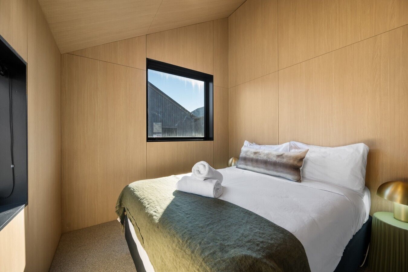 A bedroom with a bed, a window, a bedside table, and a television.