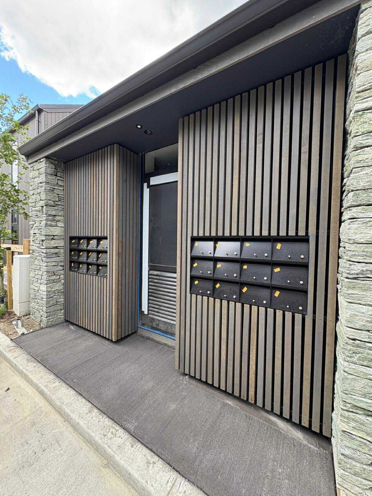 Un edificio moderno con fachada de piedra y paneles verticales de madera.