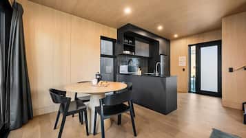 Une cuisine moderne dotée d’un îlot central, d’un coin repas avec une table ronde et des chaises, et offrant une vue à travers une porte vitrée.