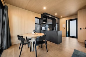 Una cocina moderna con una isla central, una zona de comedor con una mesa redonda y sillas, y vistas a través de un ventanal.