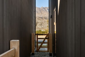 Un pasillo estrecho que conduce a una puerta con un paisaje montañoso al fondo.