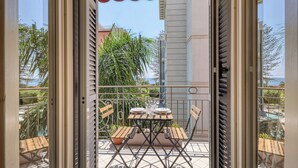 Een balkon buiten met een tafel gedekt voor twee personen, een stoel en een bloempot.
