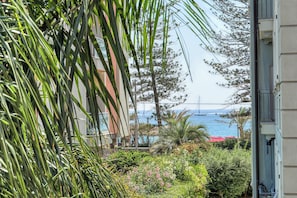 A view of a coastal area with a building, greenery, and a bridge in the distance. - Palm House apartment in elegant, central setting, a few steps from the sea. (Bordighera)