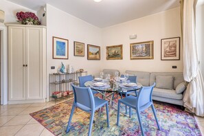 A dining area with a glass table, blue chairs, and a colorful rug.