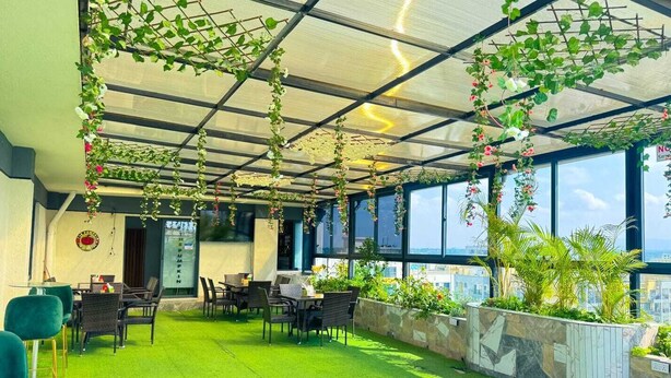 Terraza en la azotea con césped artificial, asientos exteriores y plantas colgantes.