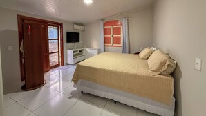 Une chambre à coucher avec un lit, une télévision, un bureau et une fenêtre avec des rideaux.