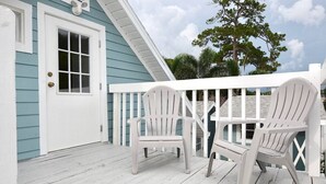 Eine Veranda mit weißen Adirondack-Stühlen und einem weißen Geländer.