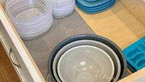 Eine Küchenschublade mit Plastikbehältern, Tellern und einer Silikon-Backmatte.