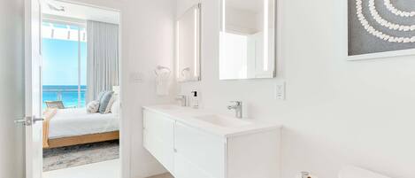 Een moderne badkamer met een witte wastafel, een grote spiegel en een toilet.