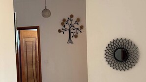 Ein Flur mit Holztür, Wanddekoration mit Baummotiv, Pendelleuchte und Sonnenstrahlspiegel.