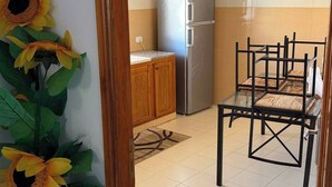 Eine Küche mit Kühlschrank, einem Esstisch mit Stühlen und einer Pendelleuchte.